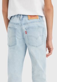 Jeans in denim blu chiaro con un classico design a cinque tasche, cuciture visibili e un'etichetta in pelle sulla vita posteriore.