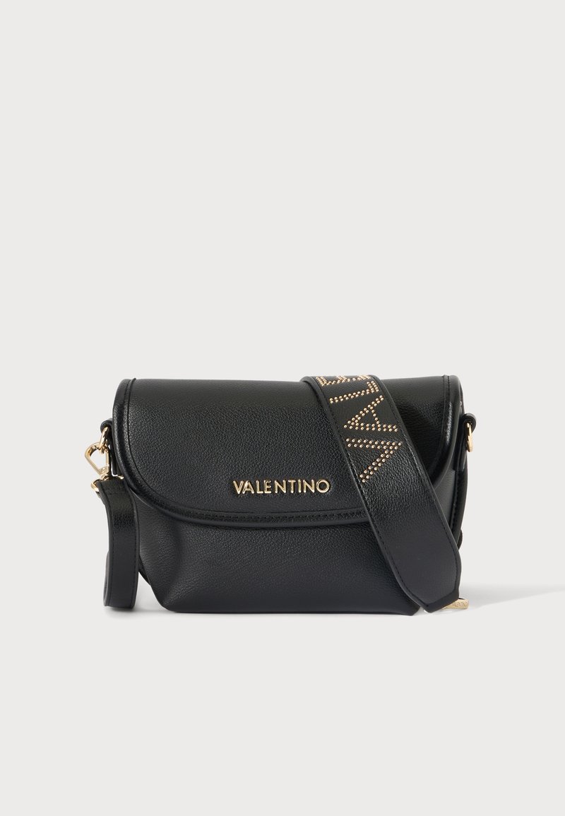 Μαύρη τσάντα Valentino χιαστί με χρυστό λογότυπο στο καπάκι και φαρδιά λουράκι διακοσμημένο με χρυσά καρφιά που σχηματίζουν γράμματα.