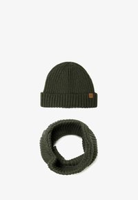 Gorro de punto en verde oscuro con textura acanalada y etiqueta de cuero, acompañado de una bufanda tubular acanalada en verde oscuro a juego.