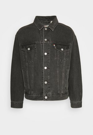 Chaqueta de mezclilla negra con cuello tipo solapa, cierre frontal de botones, dos bolsillos en el pecho y una pequeña etiqueta de logo en color. Tejido texturizado con costuras visibles.