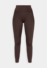 Brune leggings med høj talje lavet af elastisk stof med sidelommer og en glat tekstur. Har minimale syningsdetaljer.