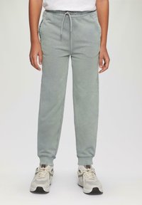 Lichtgroene joggingbroek met een elastische tailleband en trekkoord, voorzien van zijzakken en ribgebreide boorden. G gecombineerd met neutraal gekleurde sneakers.