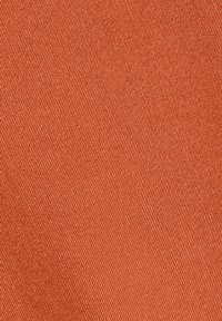 Gros plan sur un tissu orange avec une texture en sergé diagonal et des fils fins visibles.