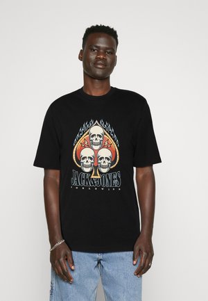 Camiseta de algodón negra con un gráfico de calavera con llamas, un diseño de as de espadas, y el texto "JACK & JONES WORLDWIDE" en letras coloridas.