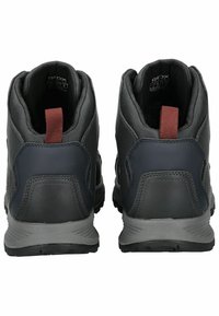 Botas de senderismo negras con una suela gris, con un acabado texturizado y una lengüeta marrón. Diseño de caña alta para soporte del tobillo.