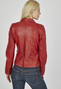 Rote Lederjacke mit tailliertem Design, sichtbaren Nähten und Reißverschlussärmeln, kombiniert mit dunkelblauen Jeans.