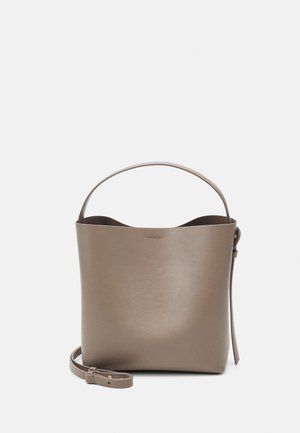 Sac seau en cuir taupe avec une seule poignée et une bandoulière ajustable et amovible sur un fond uni.