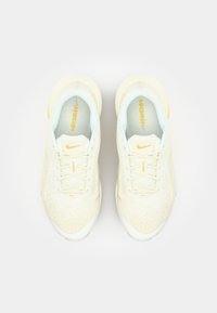 Lichtgele sportieve sneakers met een textuur bovenkant, witte tussenzool en gele accenten. Veters en merknamen in bijpassende kleuren.