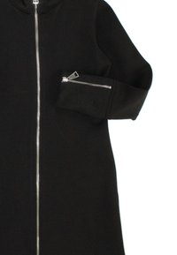 Giacchetto zip nero con colletto alto, dotato di una cerniera argentata e una tasca con zip sul manica sinistra, realizzato in un morbido tessuto texturizzato.