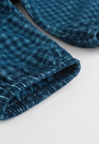 Tissu à carreaux bleus avec bords élastiqués, présentant un tissage texturé et des rayures bleu clair contrastantes.