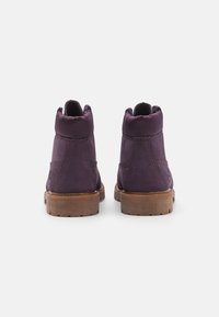 Botines de ante morados con un collar acolchado, costuras texturizadas y una suela de goma marrón claro. Parte trasera reforzada para mayor soporte.