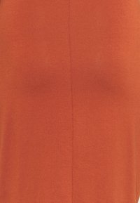 Débardeur coloris rouille en tissu doux au toucher lisse, avec un détail de couture centrale et une conception sans manches.