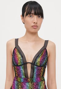 Bodysuit avec motif en peau de serpent coloré, décolleté en V profond, doté de bretelles et d'accents noirs, mettant en valeur des teintes vibrantes de l'arc-en-ciel et une texture saisissante.