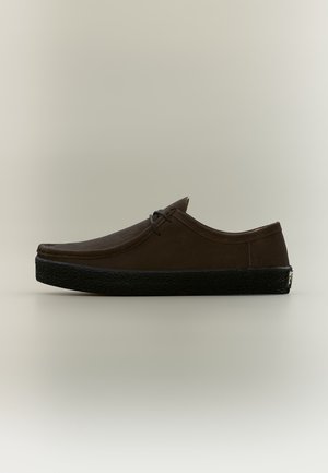 Chaussure marron décontractée à lacets avec semelle épaisse noire texturée, vue de profil sur un fond neutre.
