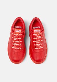 Scarpe in pelle rossa con finitura texture, caratterizzate da una punta arrotondata, lacci decorativi e accenti con il marchio sulla linguetta e sui lacci.