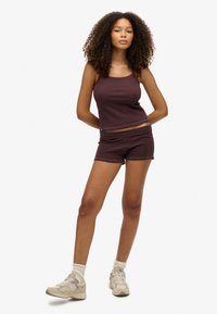Twee-delig sportset bestaande uit een aansluitend, mouwloos topje en hoge shorts in donker maroon met dunne meerkleurige strepen. Zachte stof.