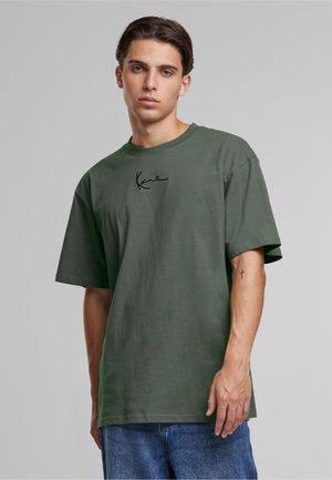 Olive green t-shirt made of cotton with a crew neck and short sleeves, featuring a black signature graphic on the front and relaxed fit.