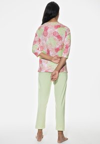 Pajama set featuring a pink floral print top with red pineapples and green leaves, and light green pants, made from soft, breathable fabric.