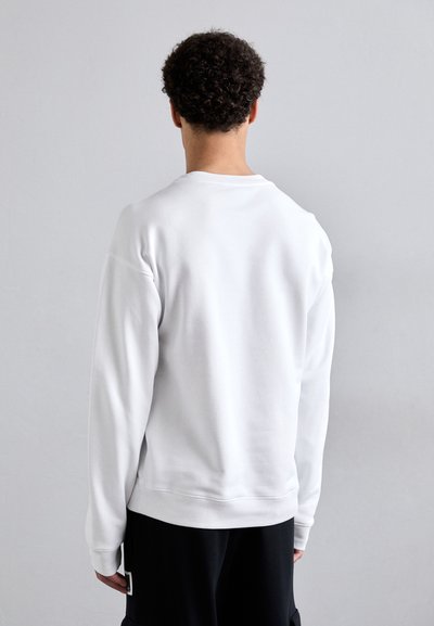 Sudadera blanca con cuello redondo y mangas largas, que presenta una textura suave y un corte relajado, mostrada desde la parte trasera.