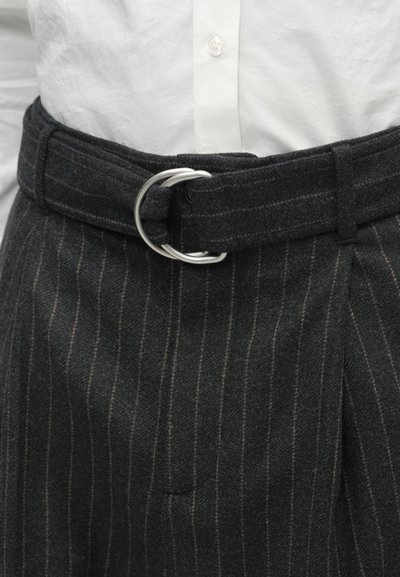 Zwarte wollen broek met streepjes en een brede riem met een zilveren D-ring gesp. De stof is gestructureerd en heeft een getailleerde pasvorm.