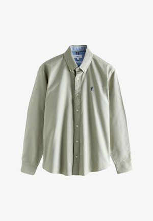 Chemise vert clair en coton, avec un col pointu, des manches longues et un petit logo bleu sur le côté gauche de la poitrine.
