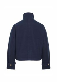 Marineblå cropped jakke med høy krage, brede ermer og knappede mansjetter, laget av glatt stoff med minimale sømdetaljer.
