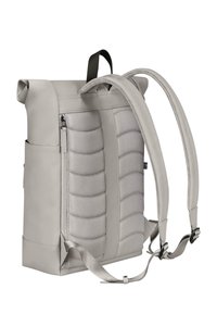 Rucsac gri cu închidere rulată, cu textură moale, curele ajustabile, buzunar lateral cu fermoar și material neted. Are o formă rectangulară fermă.