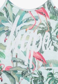 Ljusblå tanktopp med ett tropiskt tryck av gröna blad och rosa flamingos, med ordet "hopp" tydligt visat i vitt.