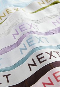 Verschiedene dehnbare Stoff-Unterwäsche in Pastellfarben. Jede hat einen breiten Bund mit dem Aufdruck "NEXT" in verschiedenen Farben.