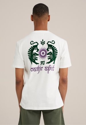 Biała bawełniana koszulka z krótkim rękawem z grafiką dwóch lwów w zielonym i purpurowym kolorze oraz stylizowanym napisem „ostjisk spirit” na plecach. Luźny krój.