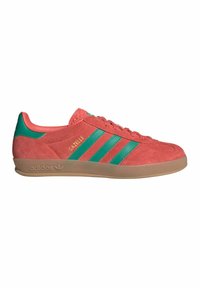 Tenisky Adidas Gazelle v koralovom semišovom materiále s zelenými pruhmi a akcentmi, vybavené gumovou podrážkou a klasickým šnurovaním.