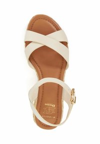 Beige cross-strap sandal with a tan cushioned footbed, a woven wedge heel, and a gold buckle accent on the ankle strap.