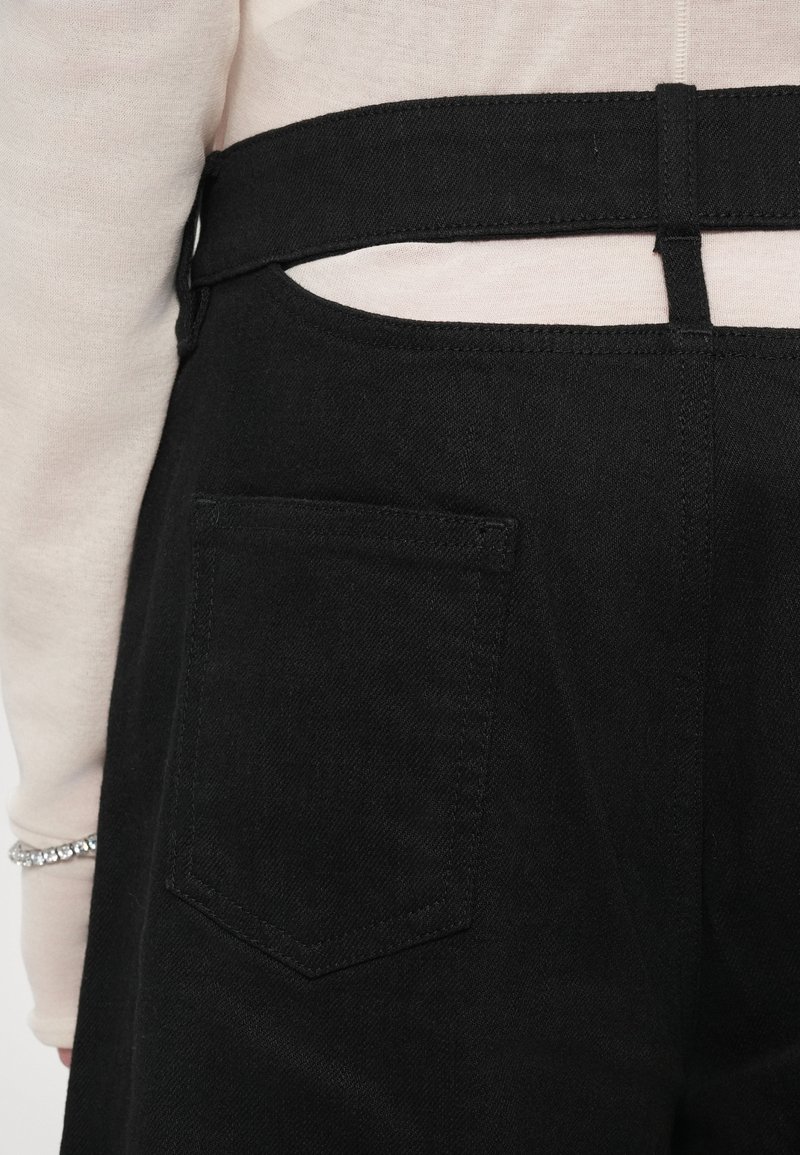 Zwarte denim salopettes met een achterzak, smalle riem en uitsnijding. De stof heeft een soepele textuur en is van gemiddeld gewicht.