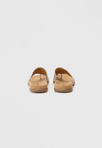 Σανδάλια slide με ανάγλυφο, ανοιχτό καφέ επάνω μέρος και λείο, μαύρο πέλμα. Ανοικτή πλάτη και περιοχή δακτύλων, μινιμαλιστικός σχεδιασμός, διακριτικές ραφές.