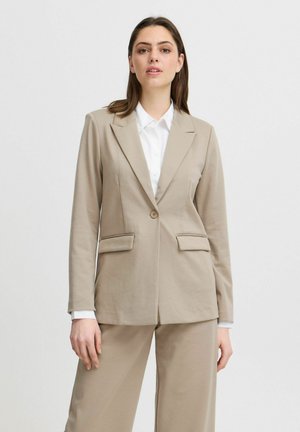 Bežový přizpůsobený blazer s jedním knoflíkem, klopovými límci a dvěma předními kapsami. V kombinaci s odpovídajícími širokými kalhotami. Směs bavlny.