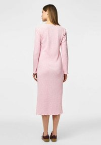 Roza rebrasta obleka s dolgimi rokavi in1im robom ter subtilnim cvetličnim vzorcem, pogledana s hrbta. Material se zdi mehak in prilega.