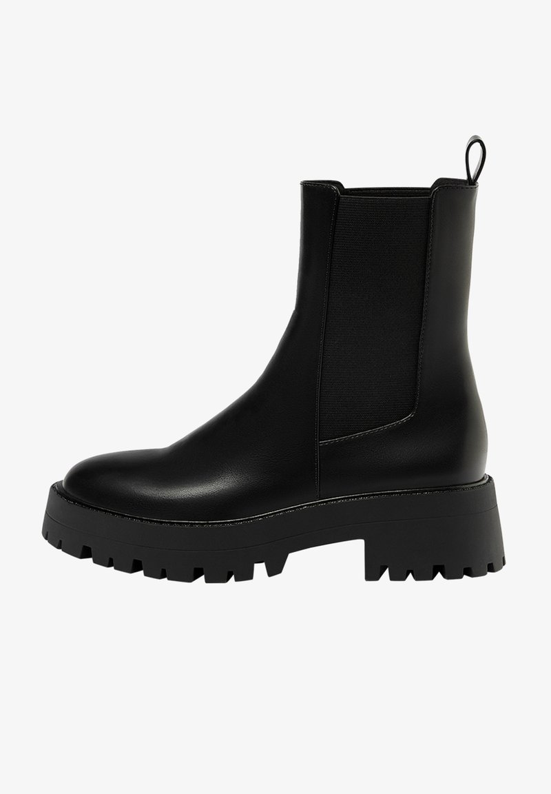 Bottine en cuir noir avec semelle crantée épaisse, panneau latéral élastique, languette à l'arrière et bout arrondi.