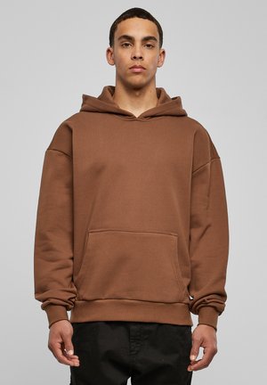 Sudadera de algodón marrón con un espacioso bolsillo canguro, puños acanalados y capucha. Corte sencillo y relajado con una textura suave y mate.