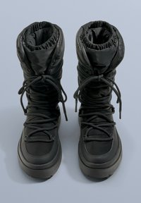 Czarne, izolowane buty z miękką cholewką, zgromadzoną przy mankiecie. Posiadają okrągłe sznurowadła i grubą, teksturowaną podeszwę zapewniającą przyczepność.