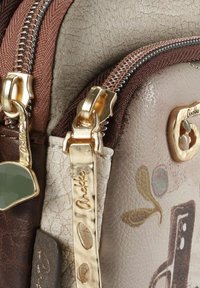 Braune und cremefarbene Ledertasche mit goldfarbenen Beschlägen, ausgestattet mit zwei Reißverschlüssen und einem dezenten Blumenmuster auf der Oberfläche.