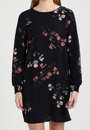 Robe bleu marine foncé avec de longues manches bouffantes, ornée de motifs floraux en rose et blanc. Tissu lisse avec des poignets froncés et un col rond.