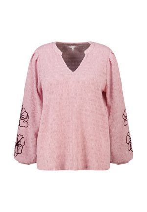 Blouse rose texturée à manches longues avec encolure en V et broderie florale noire sur les manches, taille moyenne.