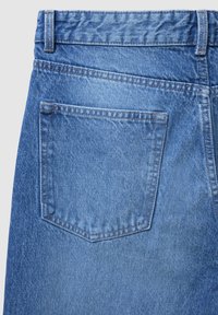 Jeans in denim blu con dettagli nella tasca posteriore, caratterizzati da un tessuto testurizzato e cuciture a contrasto lungo le cuciture.