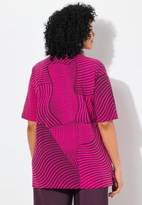 Camiseta de manga corta en rosa y morado oscuro con un patrón de rayas onduladas. Corte relajado, dobladillo curvado y dos bolsillos traseros. Fabricada con una tela suave.