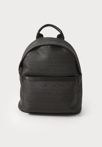 Sac à dos noir avec un design de logo en relief. Comprend une poche zippée à l'avant, une forme arrondie et deux bretelles ajustables pour le transport.
