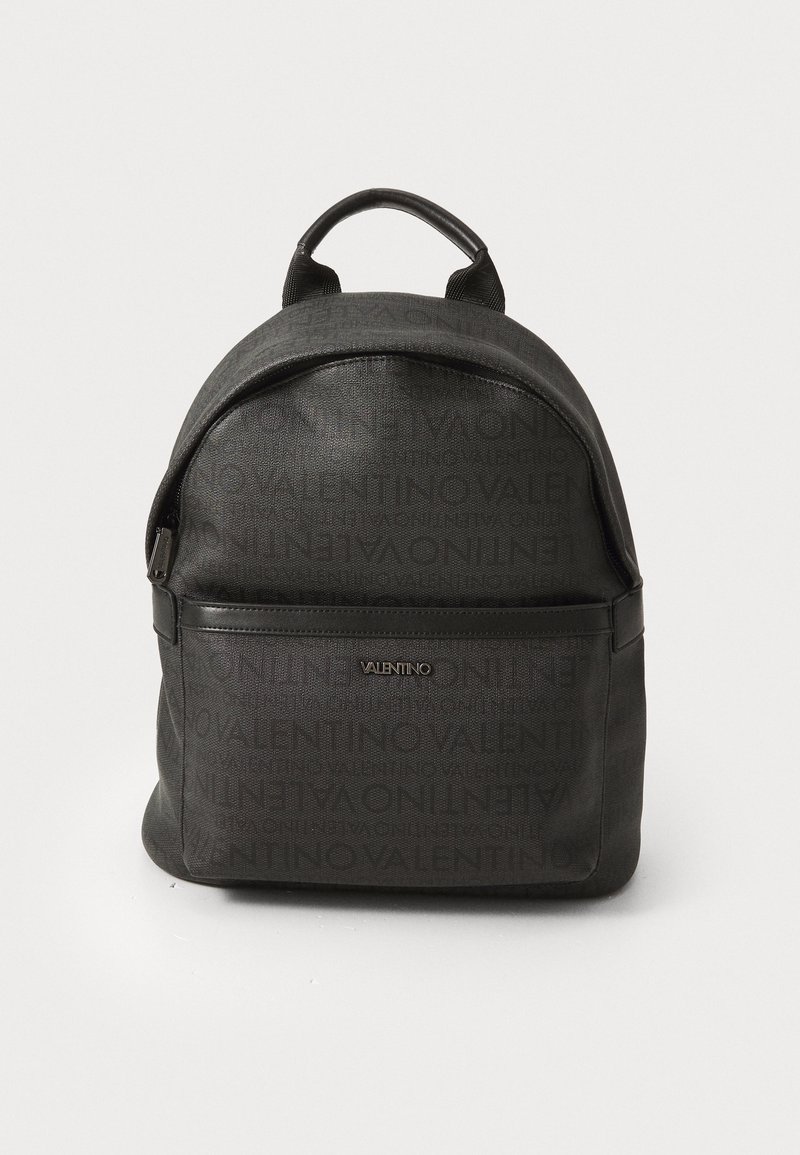 Sac à dos noir avec un design de logo en relief. Comprend une poche zippée à l'avant, une forme arrondie et deux bretelles ajustables pour le transport.