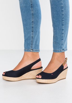 Czarne koturny z odkrytymi palcami i paskiem typu slingback, z plecioną juty śródpodeszwą, z beżowym akcentem na pasku i teksturowaną gumową podeszwą.