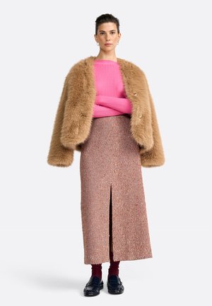 Giacca in pelliccia sintetica marrone, maglione rosa a coste, gonna midi scozzese con spacco frontale, mocassini neri e calze bordeaux. Sfondo neutro.