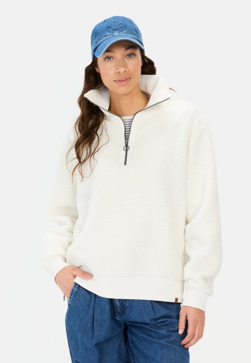 Witte fleece pullover met een half-rits kraag en ribbelmanchetten. Draag het over een zwart-wit gestreept topje. Een denim pet maakt de look compleet.