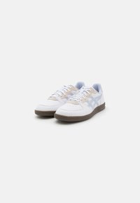 Adidași din piele albă cu accente bej și bleu deschis, închidere cu șireturi, vârf rotund, talpă din cauciuc texturat și detalii perforate.